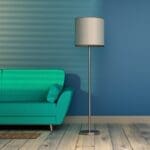 Zielona sofa przy niebieskiej ścianie z lampą stojącą w salonie