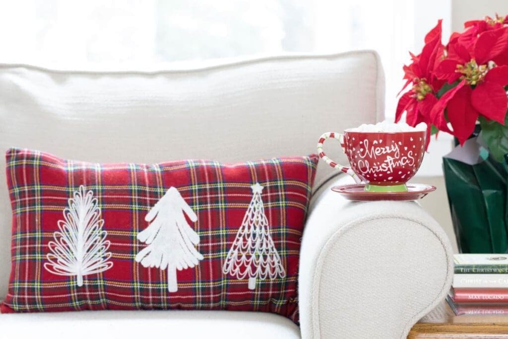 Czerwona świąteczna poszewka w kratę na jasnej kanapie, bożonarodzeniowa aranżacja salonu