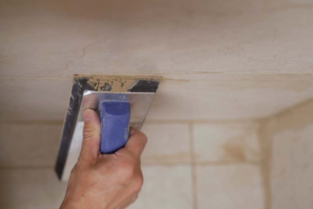 Rozprowadzanie fugi epoksydowej pacą po powierzchni płytek ceramicznych w trakcie fugowania