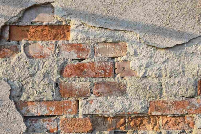 Usunięty fragment tynku odsłaniający starą cegłę na ścianie