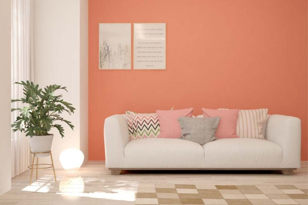 Jasny salon z koralową ścianą, białą sofą i pastelowymi poduszkami